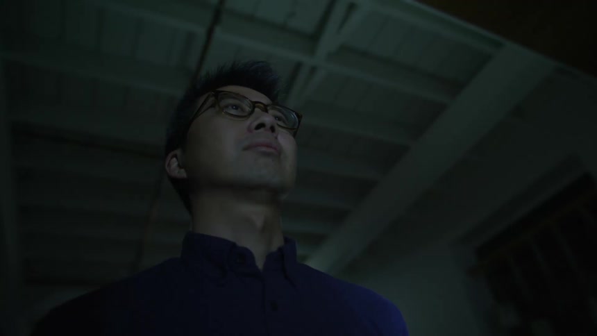 A young man wearing glasses standing inside a dark room with strobing lights