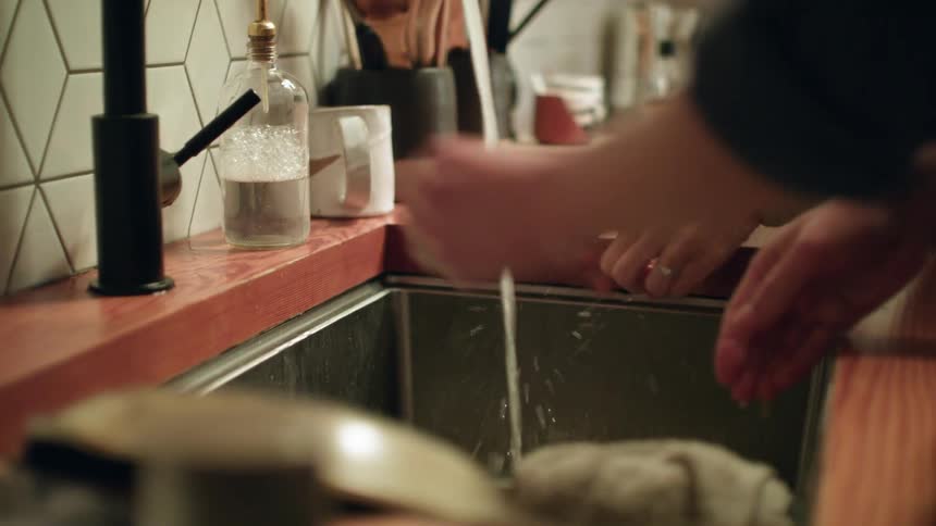 Two women clean their hands in the sink
