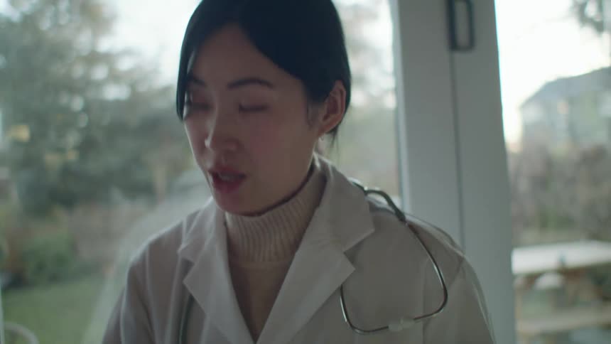 A doctor looks at paperwork while talking with another person