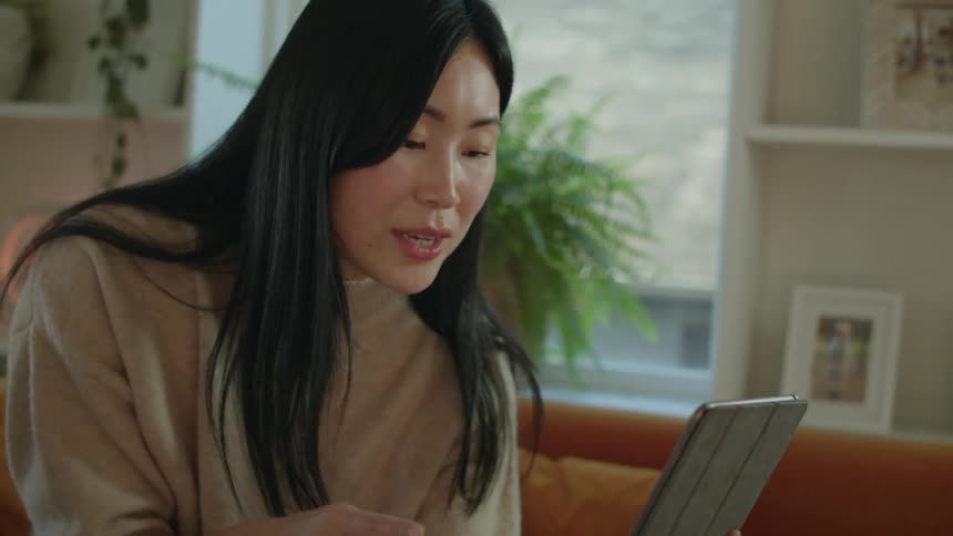 A woman talks on her tablet in her home