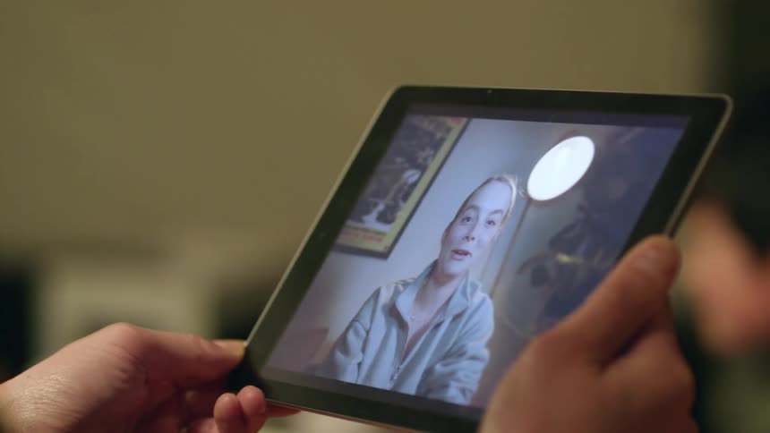 A person talking on a tablet in a house