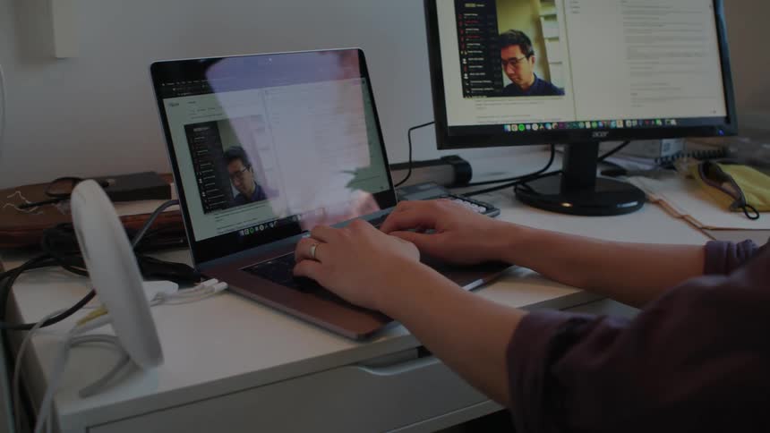A man typing on a laptop while sitting at an office desk