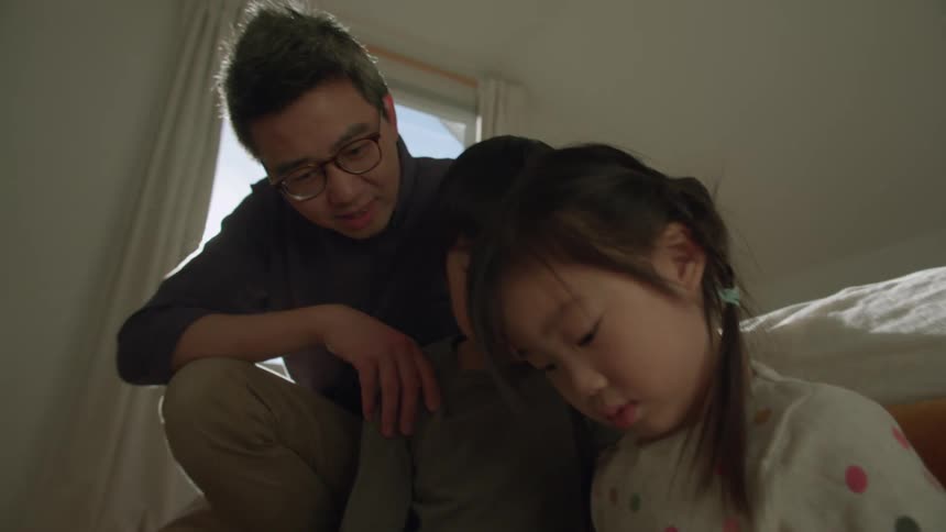 Father sits on the floor to play with his children in the bedroom at home in the morning