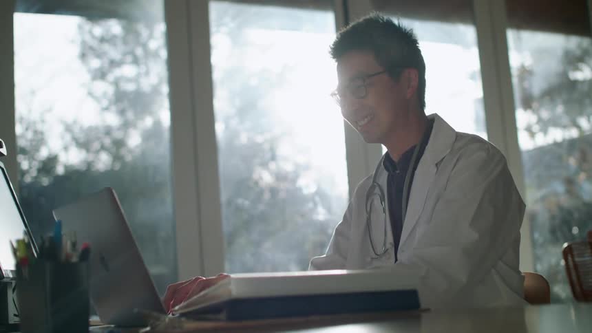 Young doctor working on a laptop from home at morning