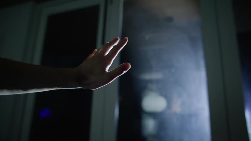 A person holds their hand out towards a door as bright lights flash
