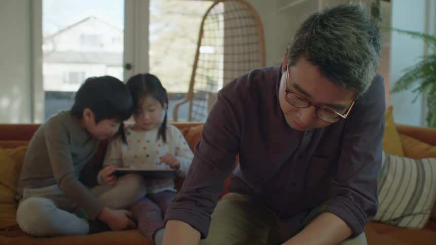 A young asian family hanging out on a living room sofa