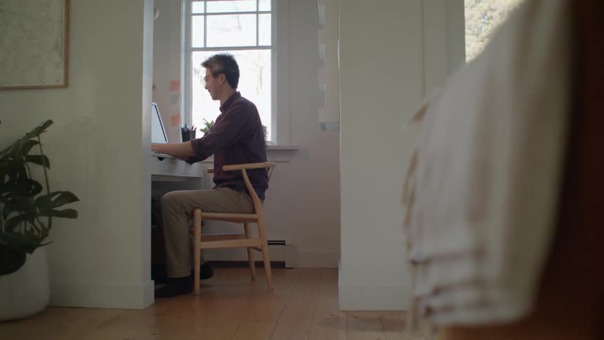 A man working on a computer in his home office at daytime