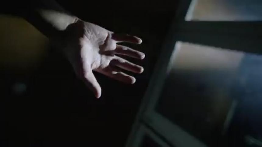 A hand lighted by white chaotic strobe lights inside a house at night