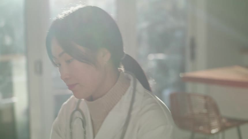 A female doctor sitting in the kitchen at home in the morning