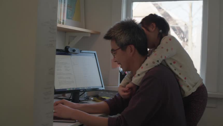 A father and daughter working at a laptop