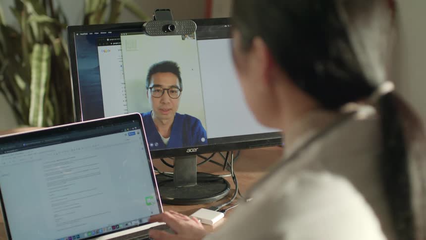 A man and woman talking on a webcam at work