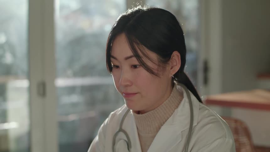 Young female doctor talking on a video call from home at morning