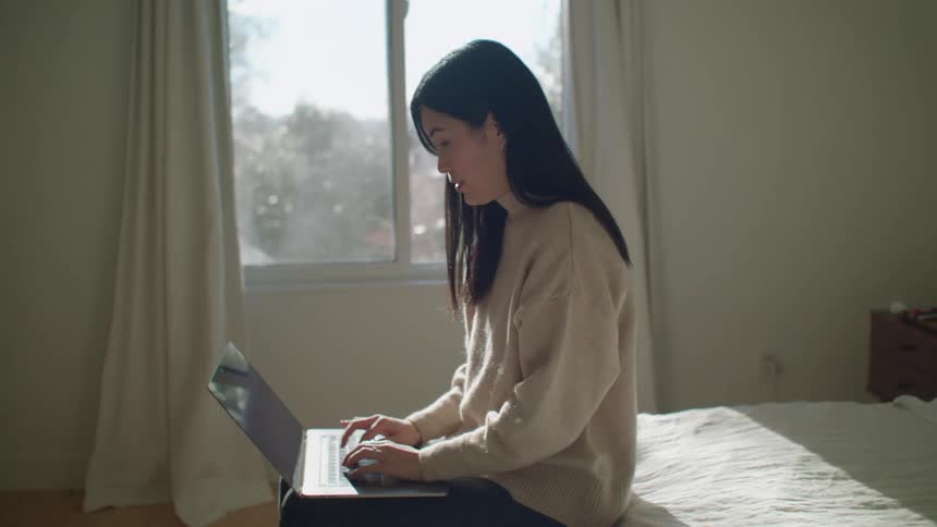 A woman sitting in a room with a laptop