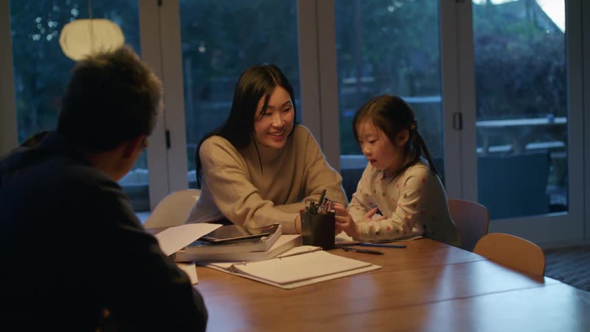 Family doing homework together on the dining room table at evening