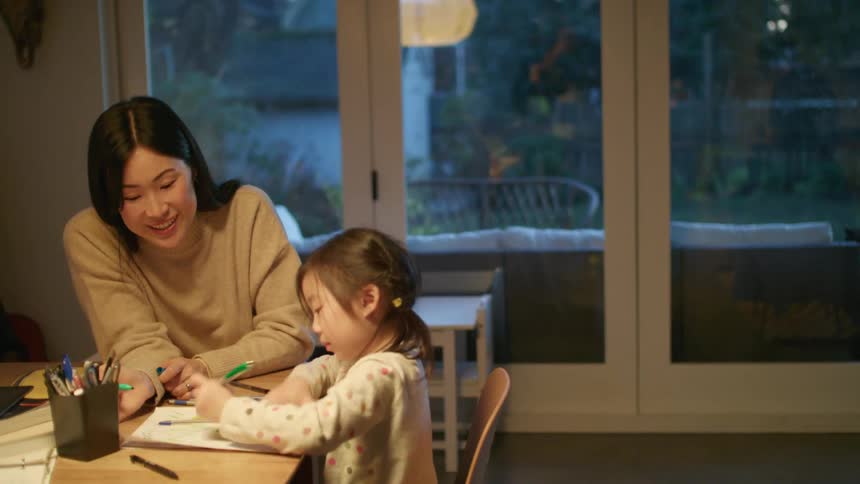 Mother helping daughter with homework on the dining table in the kitchen
