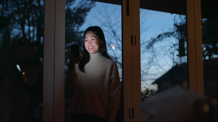 A woman at home video chats with someone on a cell phone