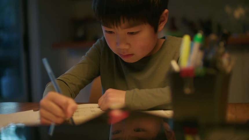 Young boy doing homework in the kitchen table at home