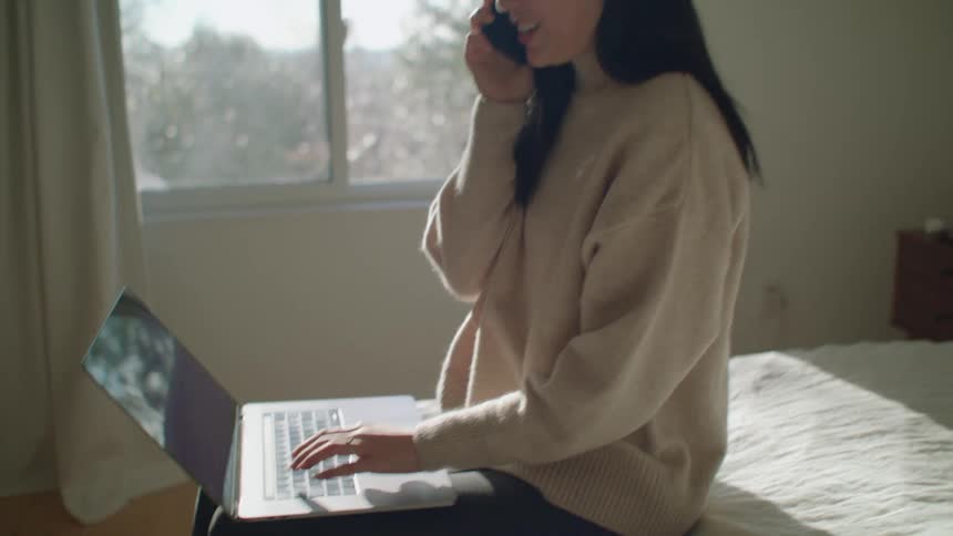 A woman using a laptop and a cell phone