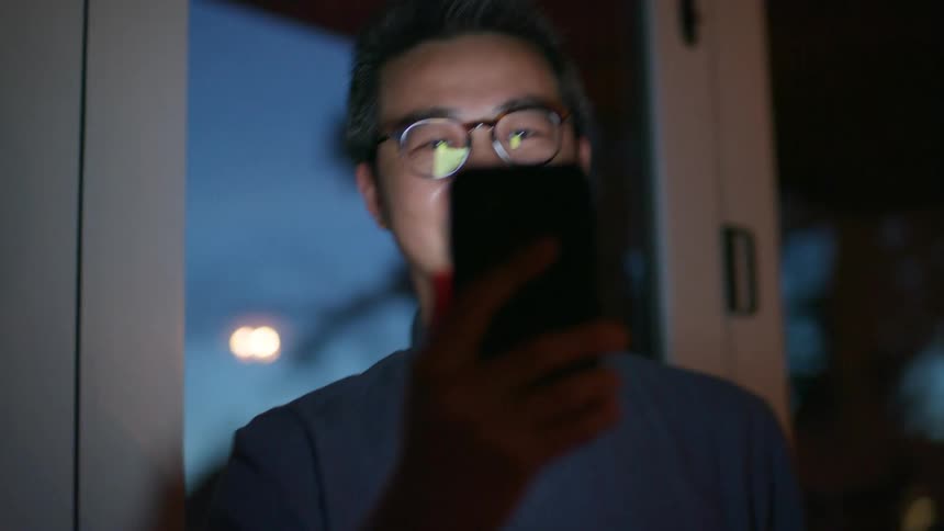 A man at home video chats on his cell phone