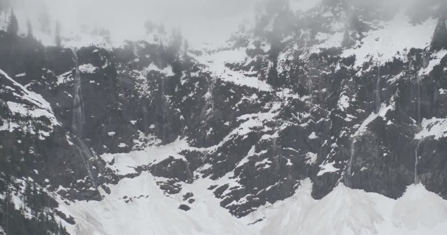 Snow falls on a mountainside