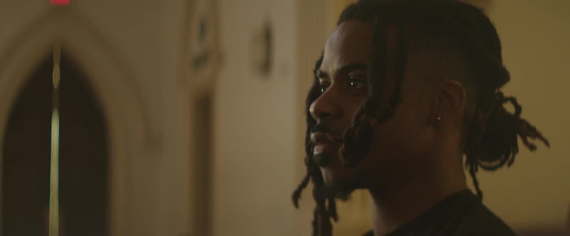 A black male teenager stands inside a building
