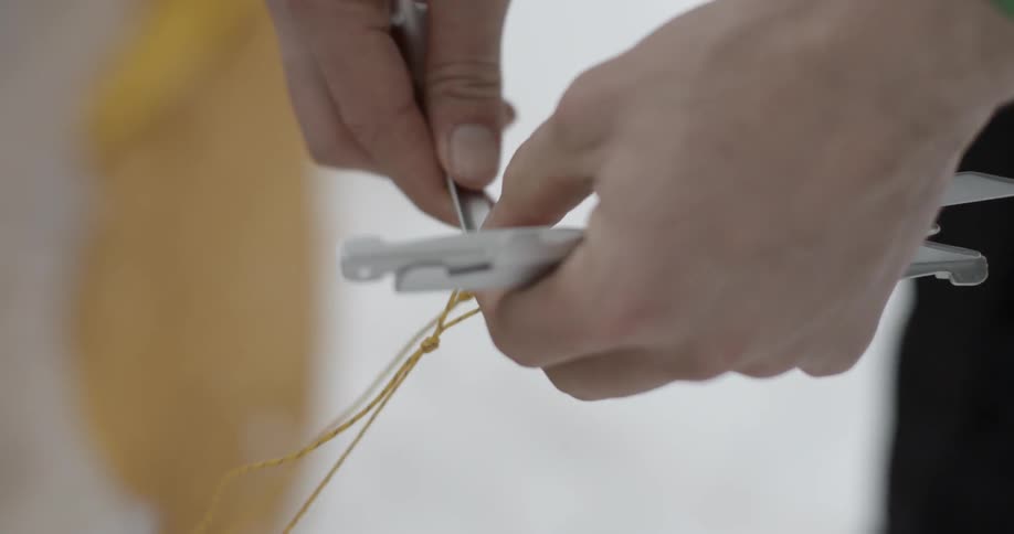 A person is putting a tent spike in string
