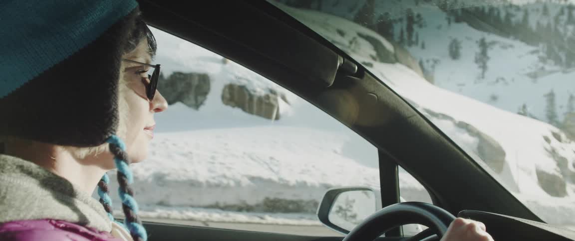 A woman driving her car in a snowy mountain range