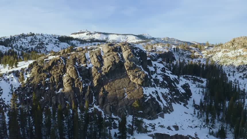Aerial view of a promontory on the snow covered mountain range in the morning