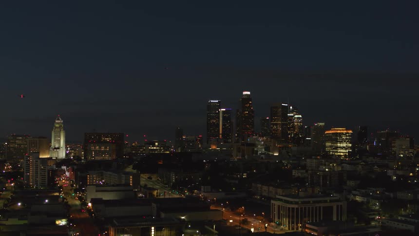 Multiple tall buildings of a downtown metropolitan area are illuminated at nighttime