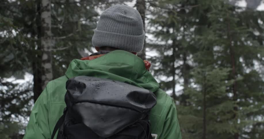A man is hiking in a snow covered forest