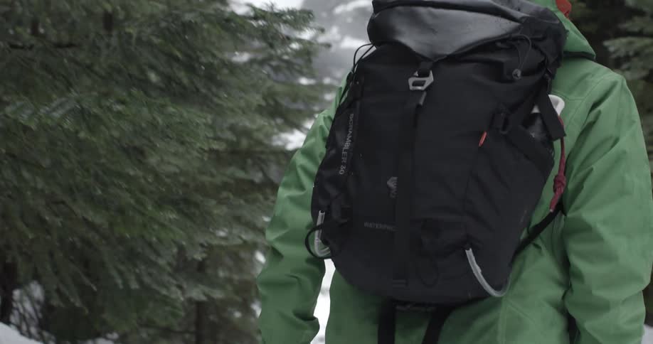 A man hiking through a mountain forest during winter