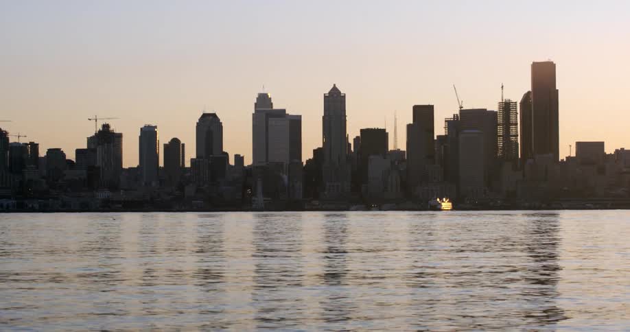 The sun is rising over a city across the water
