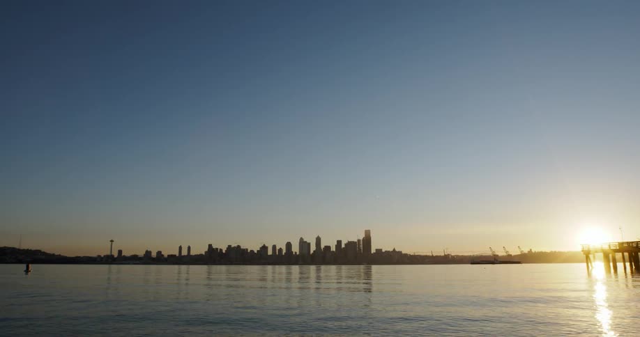 The sun is setting by a city in the distance