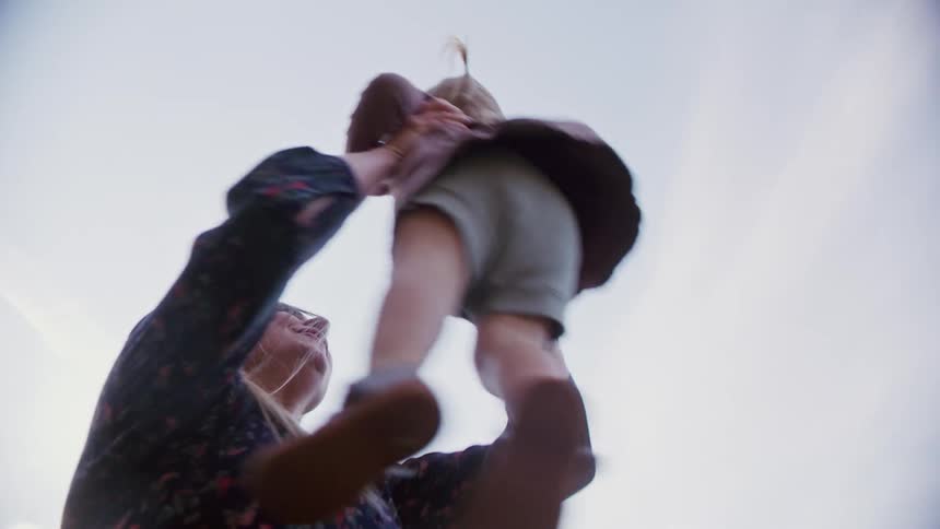 A mother is playing with her daughter outdoors during the day