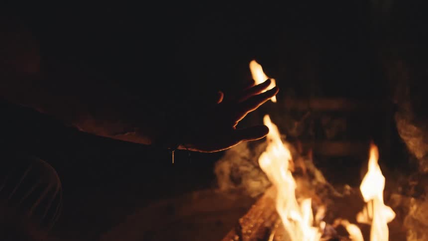 A person is sitting by the fire at night