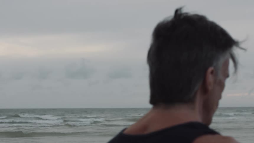 A man walking along the ocean at dawn