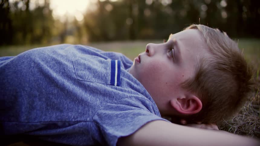 A child is laying on the grass at dusk