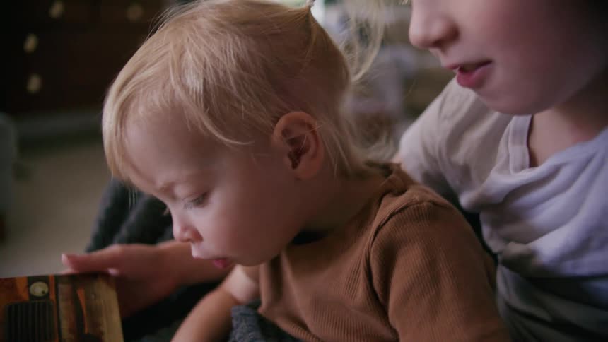 Children sit together reading a book