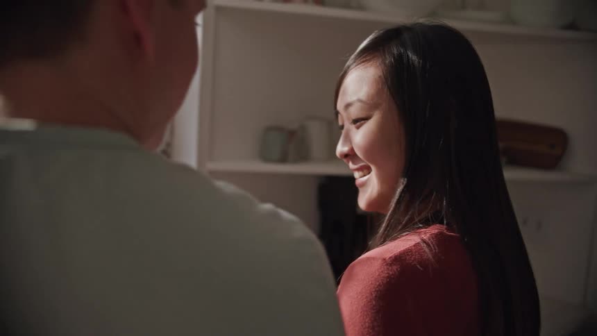 A man and woman talk and laugh in the kitchen