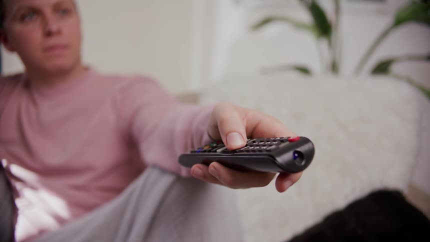 A man sits on the couch with a woman using a television remote
