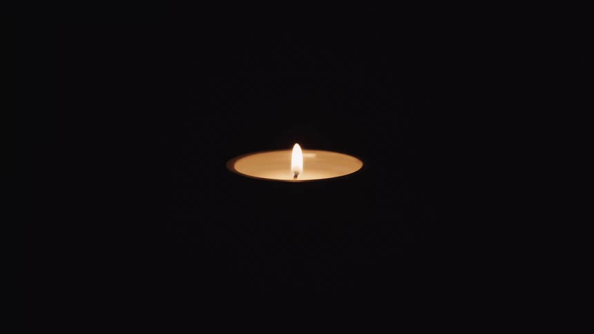 A flaming candle in a round holder is blown out