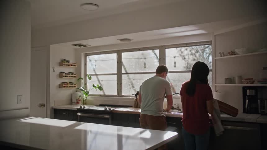 A man and woman do dishes in the kitchen