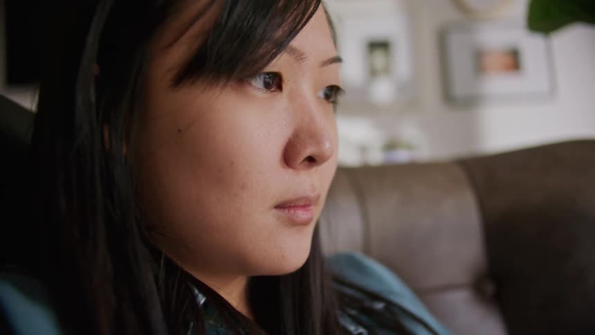 A woman in a room sitting on the couch with a wall in the background