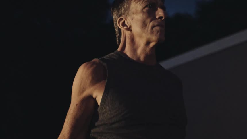 An older male jumps rope very quickly while outdoors at night
