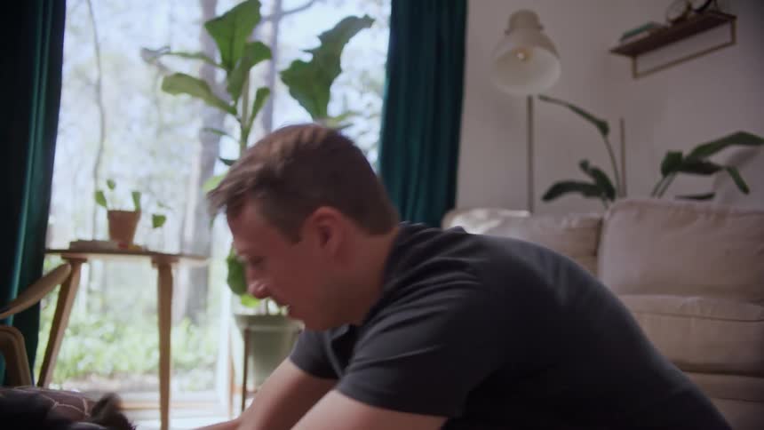 A man is playing with his dog indoors