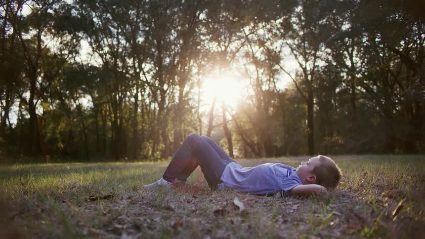 A child laying down in a field on some grass
