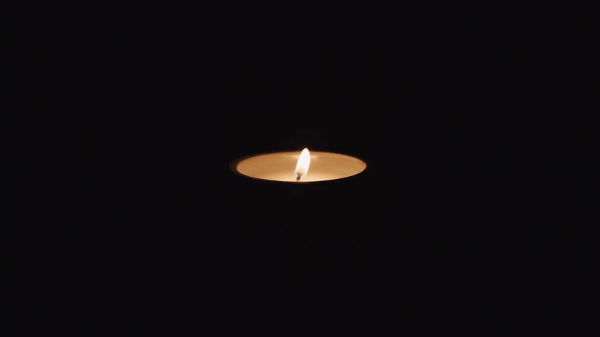 A candle with fire burning in the darkness
