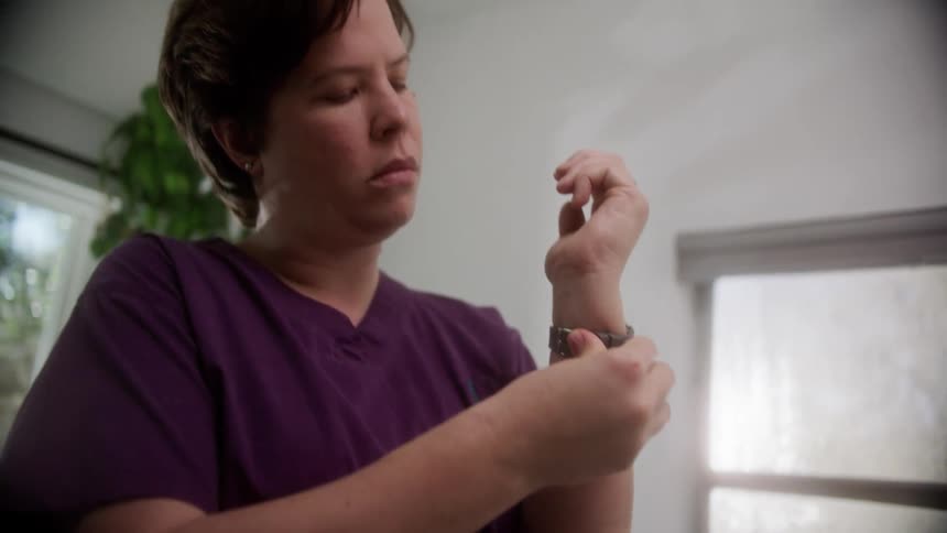 A nurse in scrubs putting on her watch