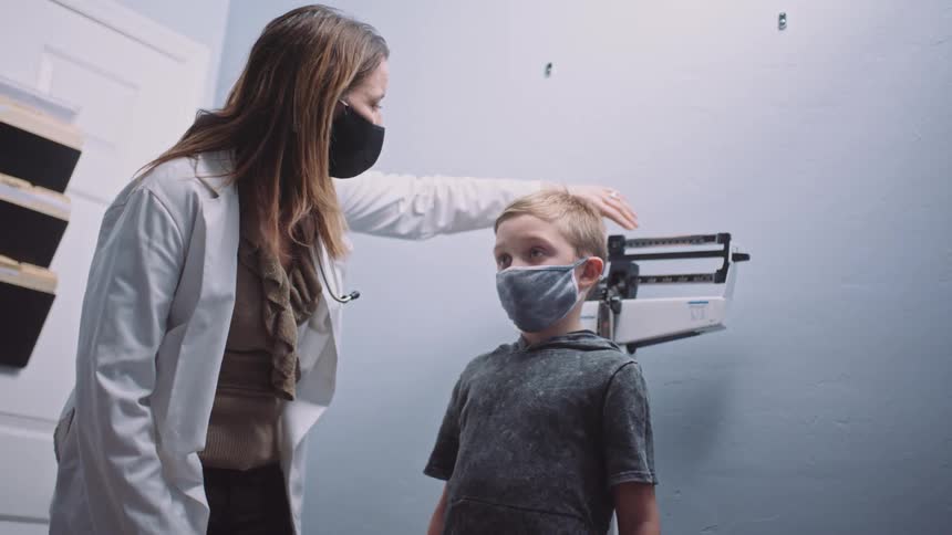 A doctor weighs a young boy in a clinic
