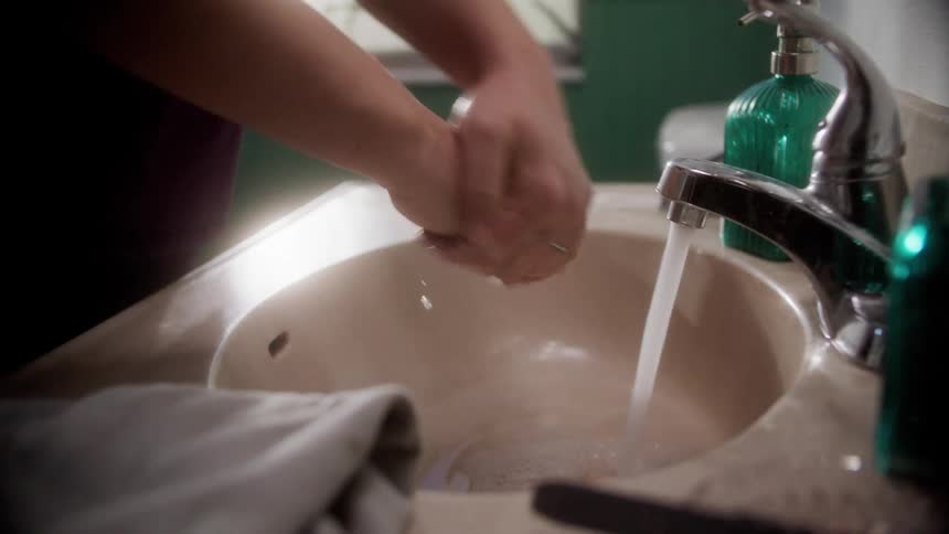 A female home healthcare nurse looks in the mirror just before washing her hands